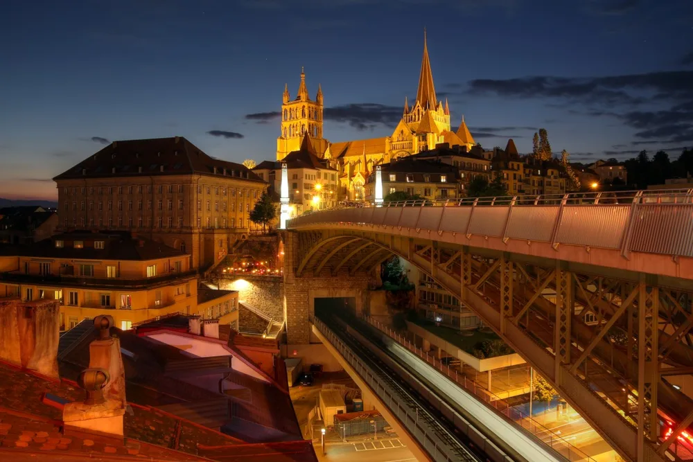 The cathedral of Lausanne lit at night above the city